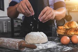 Man sprinkles flour over fresh dough photo