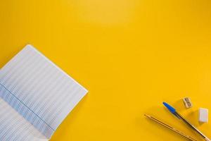 Notebook, pen, pencil, eraser, and sharpener on yellow background photo