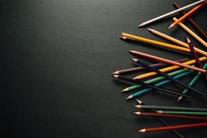 Colorful pencils on one side of dark background photo