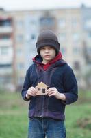 niño sin hogar sosteniendo una casa de cartón foto