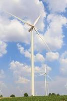 Wind turbine on the green grass over  blue clouded sky photo
