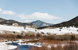 Snowy field and stream by mountain photo