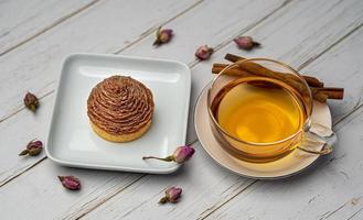 Cupcake on white ceramic plate and cup of tea with cinnamon photo