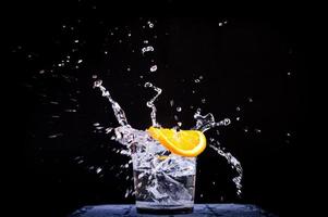 Splash of water in glass with sliced lemon photo