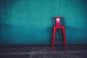 Red metal chair against blue wall photo