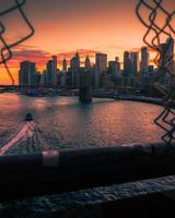un barco que pasa bajo el puente de brooklyn con el horizonte de la ciudad de nueva york foto