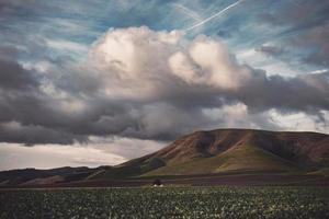 campo verde y montaña bajo el cielo nublado foto