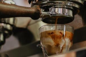 Espresso goteando en vaso de chupito foto