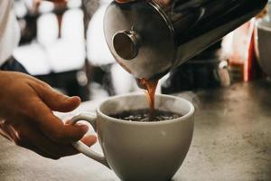Person pouring coffee in white ceramic cup photo