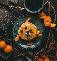 Pancakes with orange slices and blueberries on plate photo