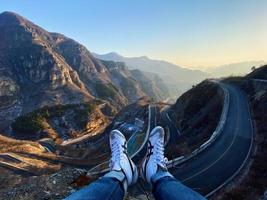 View of person's feet hanging out towards cliff photo