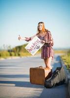 Portrait of lovely young hippie girl hitchhiking on a road photo