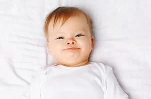 Closeup retrato lindo bebé positivo en la cama, vista superior foto