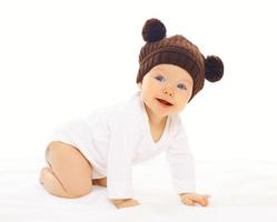 Portrait positive baby in knitted brown hat crawls