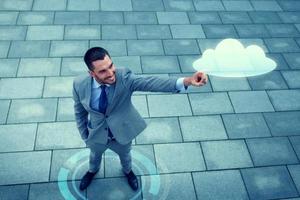 smiling businessman with cloud projection outdoors photo