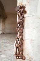 rusty iron chain hanging on brick wall of historic building photo