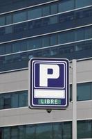 Parking signpost with libre text and modern building background photo