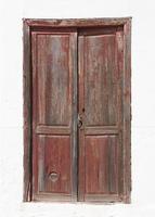 Antigua puerta de madera marrón en una fachada blanca foto