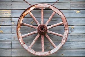 Old used wooden wheel hanging on rural wall