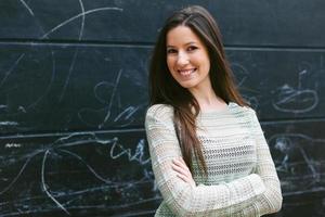 Young beautiful woman standing in front a blackboard wall. photo