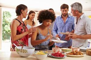 Friends serving themselves food and talking at dinner party photo