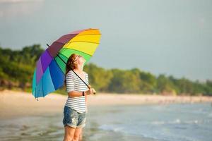 Atractiva mujer caucásica con gafas de sol sosteniendo coloridos paraguas arco iris