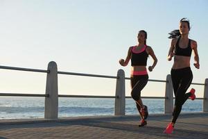 Two female athletes running outdoors fitness tracker device photo