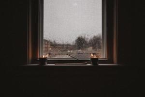 Candles on windowsill on rainy day photo