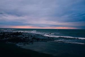 Silhouetted rocks on beach at sunset photo