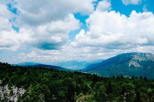 Trees and mountains under cloudy blue sky photo