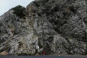 persona que toma la foto de la montaña rocosa gris