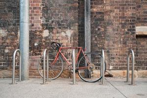 Red bike next to bike rack near wall