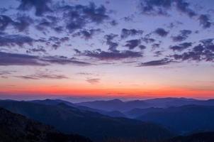 silueta de montaña contra el colorido atardecer y cielo nublado foto