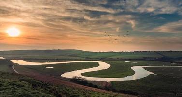 Winding stream through grassy field at sunset photo