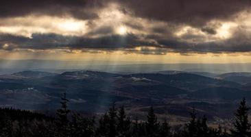 Sunbeams shining through clouds on mountains photo