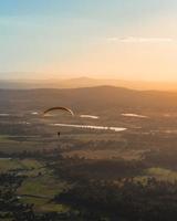 Person paragliding above countryside 