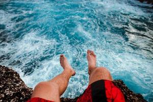 Person sitting on cliff near water photo