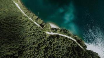 Aerial view of road by water and green forest photo