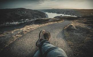 Person sitting on brown rock formation near water photo