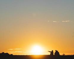 Silhouette of three people sitting  photo