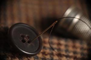 Sewing button on a tweed coat photo