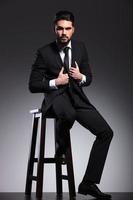 business man sitting on a stool arranging his jacket photo