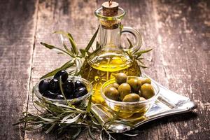 Aceite de oliva y aceitunas en mesa de madera foto