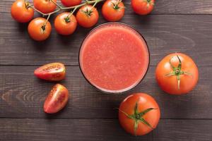 Healthy vegetable. Glass of red tomato juice on wooden table photo