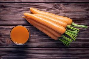 Top view of fresh carrot juice over wooden background photo