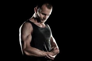 muscular man,  clasps hands in  fist, black background, place for photo