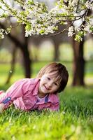 Adorable happy kid outdoors on spring day in beautiful blooming