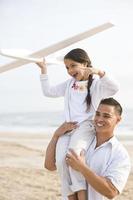 Hispanic father and daughter having fun on beach photo