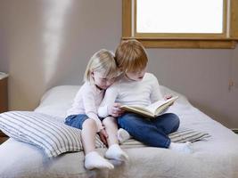 Sisters Reading Book On Bed photo