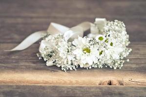 Wreath of chamomile flowers on the wooden floor photo